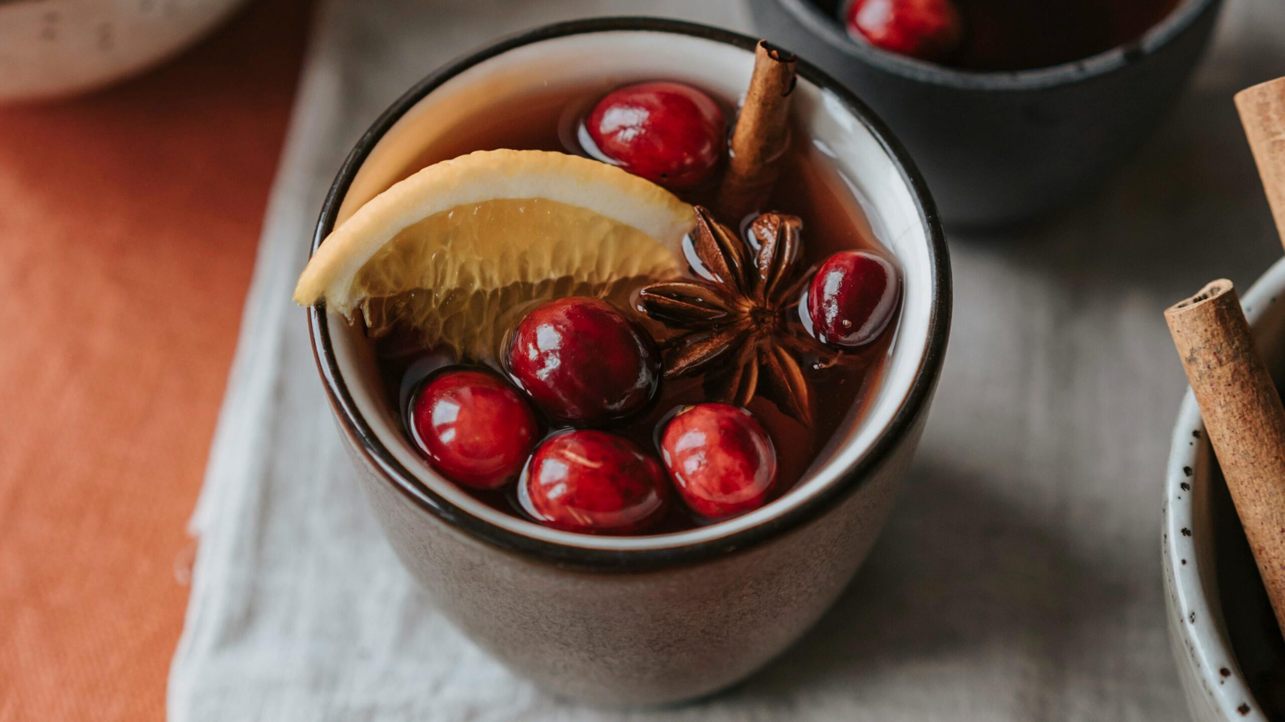 Cozy mulled wine with cranberries, star anise, and lemon wedge, perfect for warm gatherings.